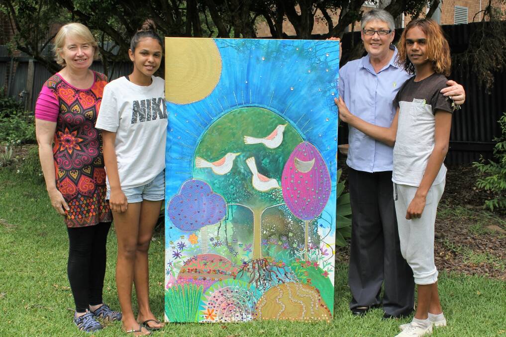 ART OF GIVING: Moree Can Assist treasurer Cathy Corderoy (left) and vice president Tricia Graham (second from right) accept the colourful painting from the artists - Rehannah Haines and Jarrowa Jerome.