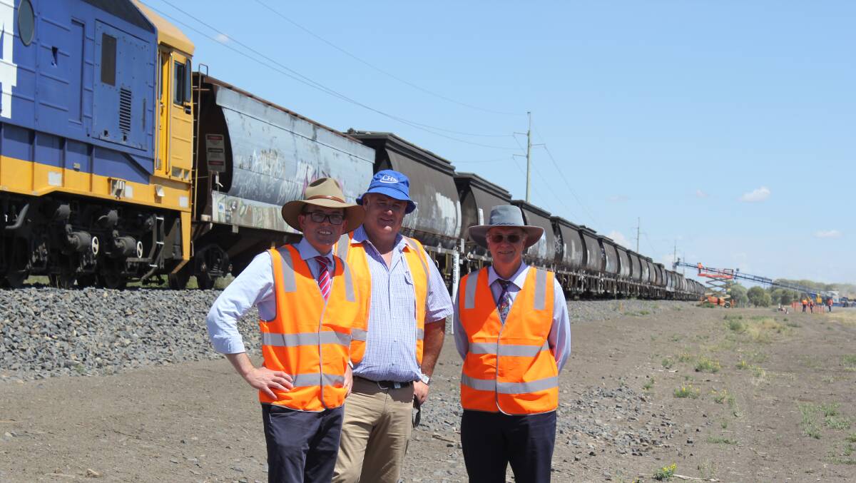 Northern Tablelands MP Adam Marshall, Broadbent Grain managing director Steve Broadbent and Moree Plains Shire Council’s John Carleton in front of the 1.3km long grain train being loaded on Friday.