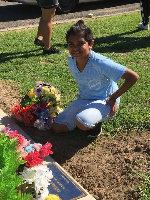 Young champion: Darryl Smith spent a small time out of his weekend cleaning flowers and placing them on old graves. Photo: Supplied