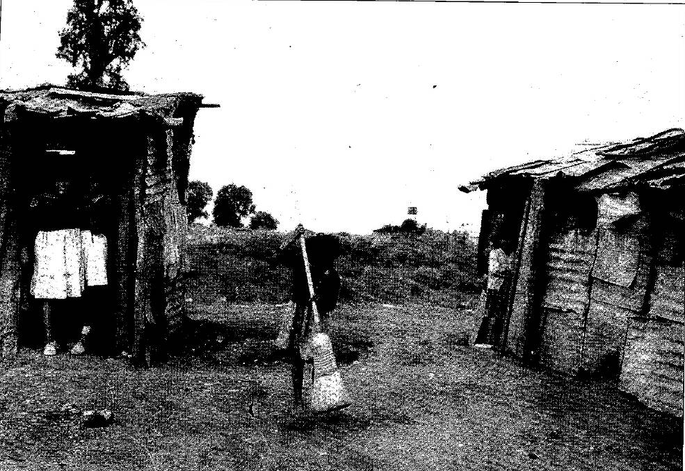 Living conditions at the Top Camp in the 1960s. Mary Craigie standing in the doorway of Annie May Cutmore's hut with her friend Cheryl Smith. Cynthia Rose Priestly busy with the straw broom and Loretta Murray in the doorway of Maude 'Polly' Murray's hut. Amelia Murray can be seen peeping through the window.