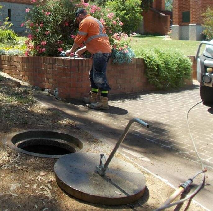 A council worker undertakes a condition assessment of a sewer manhole in town.