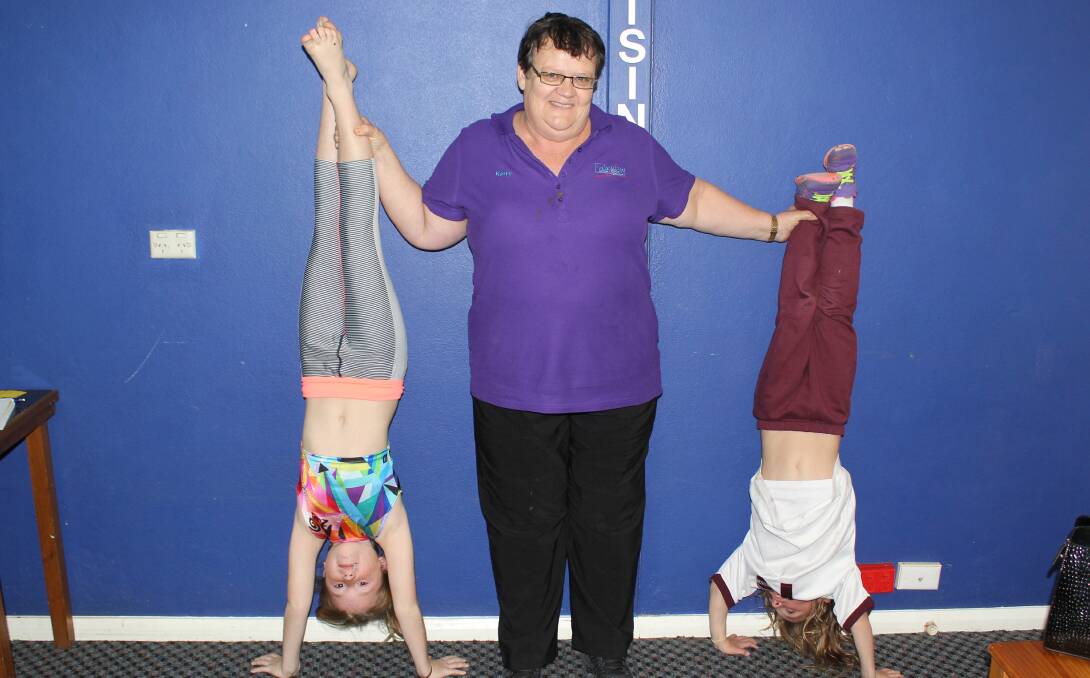 Kerry Hunt helps Isabel Schweitzer and Olivia Pinner do a head stand. Kerry has been coaching gymnastics for about 32 years.