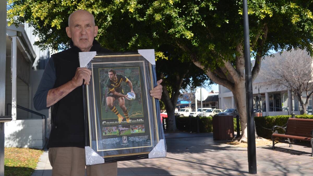 Tony Woodham carries one of the five framed prints up for auction on Sunday.