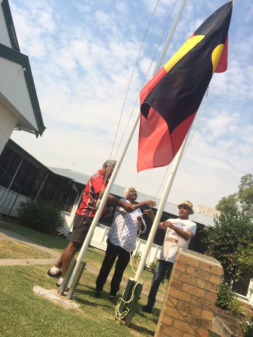 Celebration: Aunty Maureen Newman raises the flag at Pius' National Apology Day.