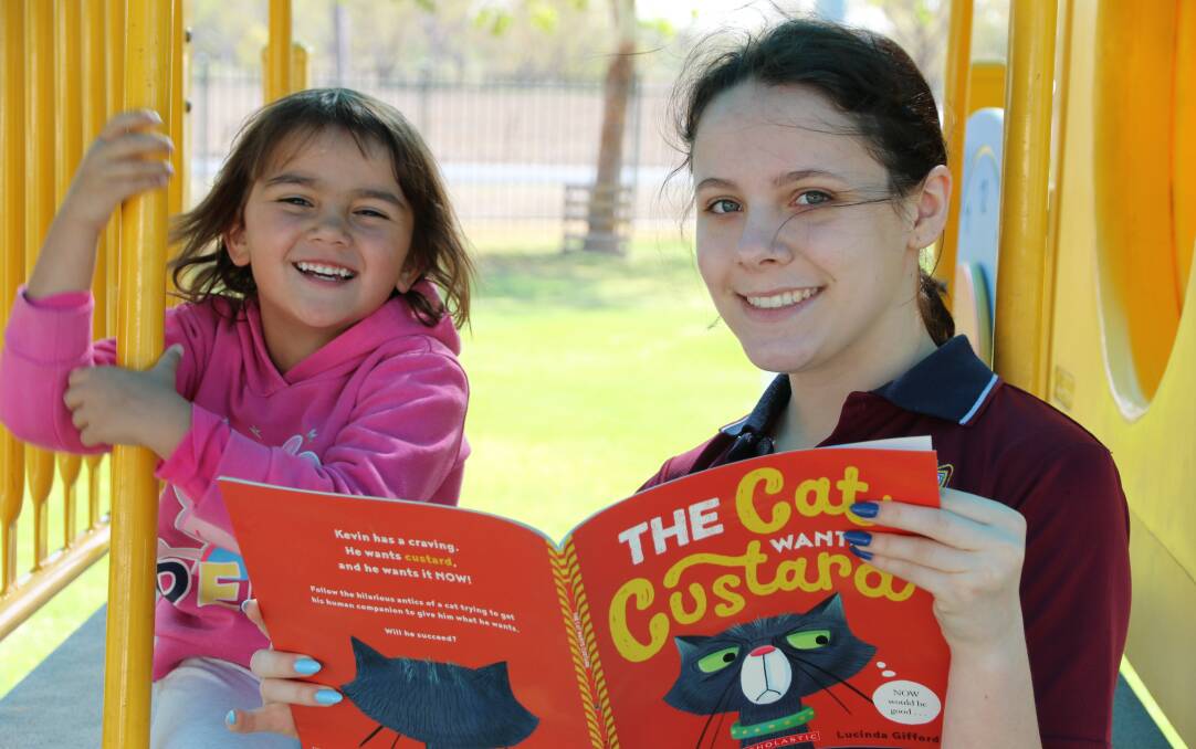 Kiah Preschool student Rae-Lisa Geale enjoying her new book with Radford College volunteer from Canberra, Holly Saunders. Photo: supplied.