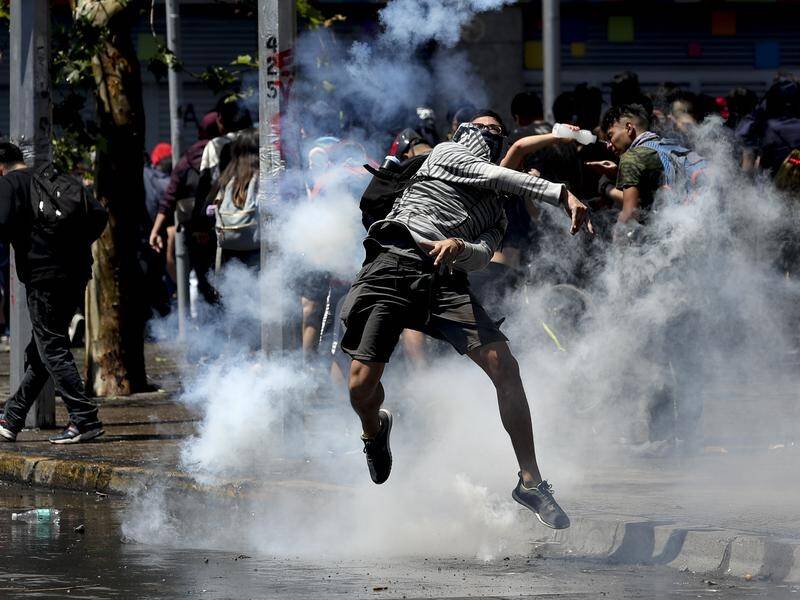 A protester returns a tear gas canister to police during clashes in Santiago, Chile.