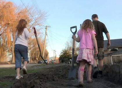 Digging in ... Gareth  Cook and his daughters Cambelle and Tasman shovel mud after their property was inundated  for a third time since September.